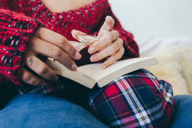 Crop femme tenant des lunettes sur le livre