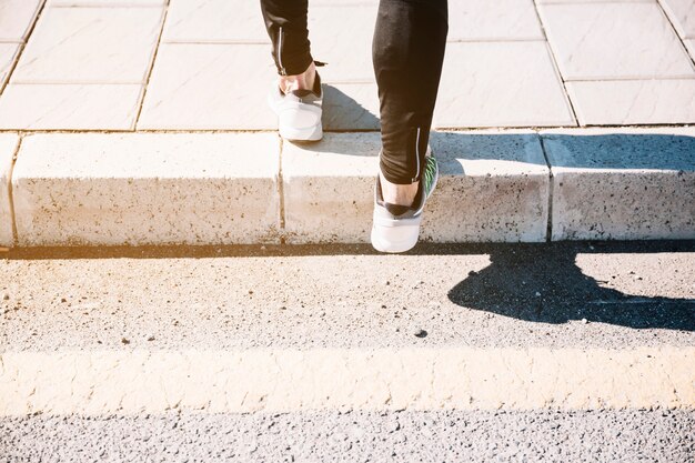 Crop jambes dans des baskets sur le trottoir