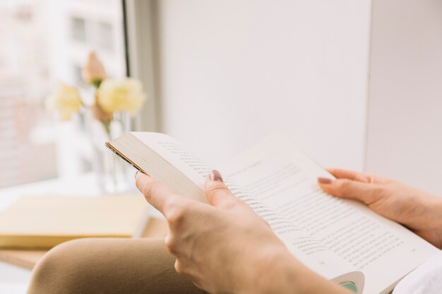 Crop lecture de femme dans le livre de lumière