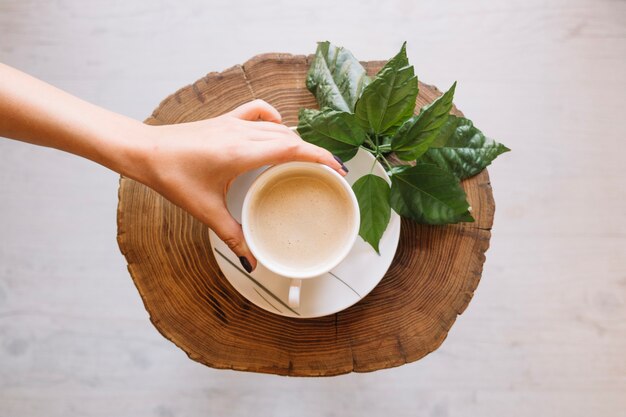 Crop main plaçant la tasse de café sur la soucoupe