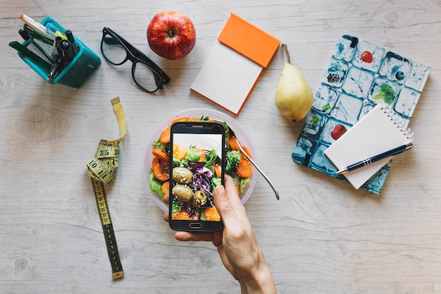 Crop main prenant la photo de la salade au bureau