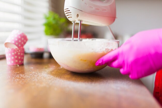 Crop mains mélangeant la pâte dans un bol en verre