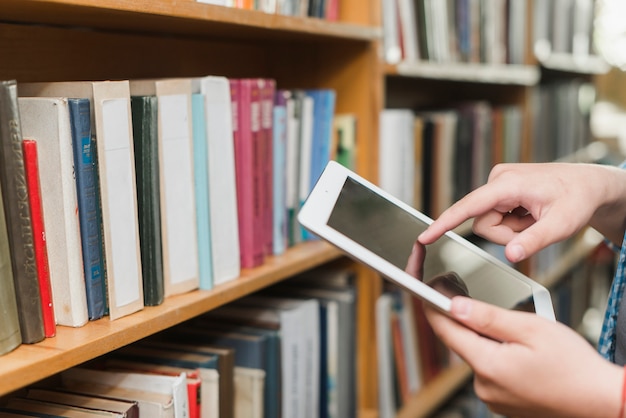 Crop mains avec tablette dans la bibliothèque