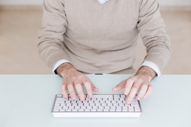 Crop man utilisant un clavier d&#39;ordinateur