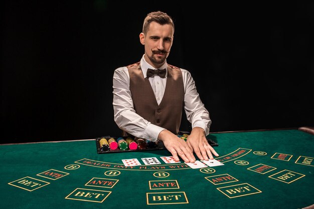 Croupier derrière une table de jeu dans un casino sur fond noir. Le concept de victoire.
