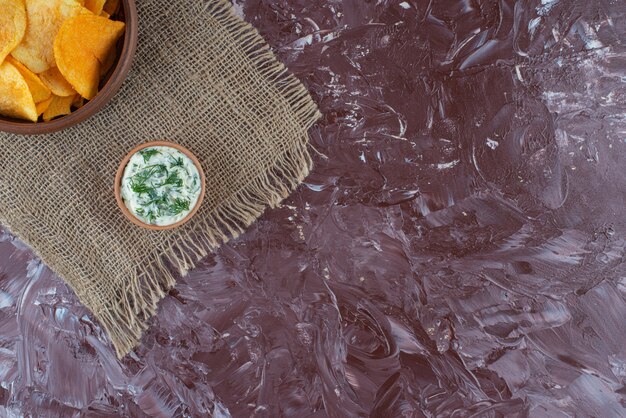 Croustilles croustillantes et yaourt dans une assiette sur la texture, sur la table en marbre.