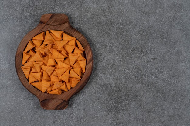 Croustilles de maïs en forme de cône à saveur de fromage dans une plaque en bois sur la surface en marbre