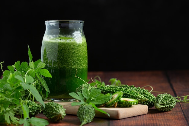 Une cruche de smoothie de courge amère avec courge amère crue mis sur planche de bois