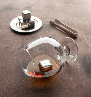 Cubes en acier imitant la glace pour rafraîchir les boissons avec un verre de whisky pince à proximité
