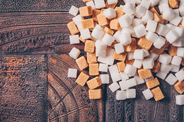 Cubes de sucre blanc et brun sur une table en bois foncé. vue de dessus.