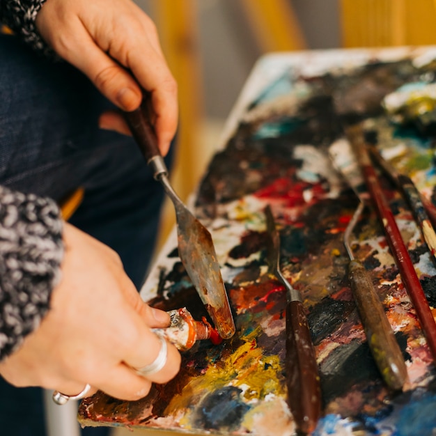 Photo gratuite cueillir les mains à l'aide d'une spatule pour prendre de la peinture