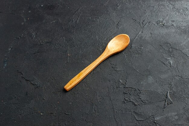 Cuillère en bois vue de dessous sur un espace libre de table sombre