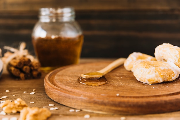 Photo gratuite cuillère de miel et beignet sur planche de bois