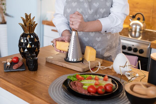 Cuiseur caucasien frotte le fromage pour différents plats sur la table