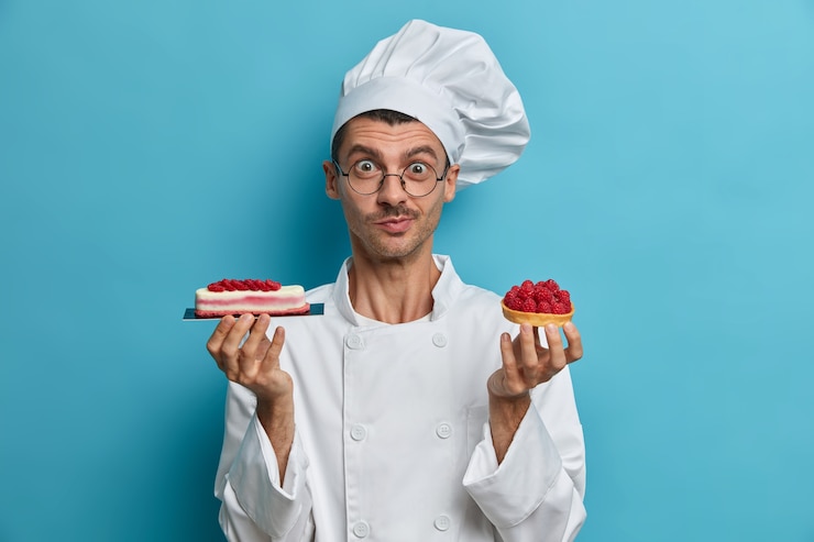 Photo gratuit cuisine, profession, concept de boulangerie. jeune homme cuisinier détient de savoureuses confiseries, desserts décorés de baies