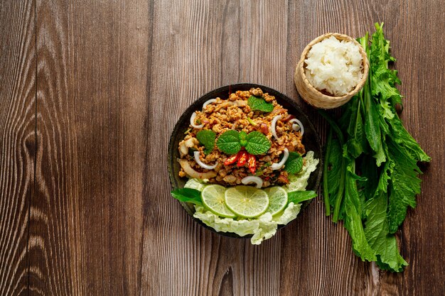 Cuisine thaïlandaise avec du porc haché épicé servi avec des plats d'accompagnement et du riz gluant