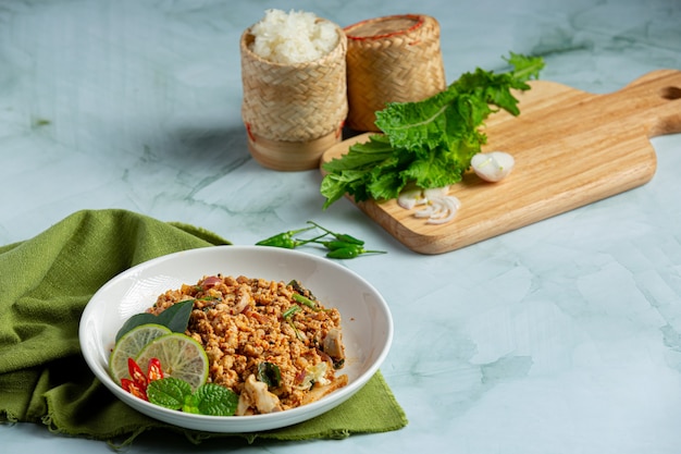 Cuisine thaïlandaise avec du porc haché épicé servi avec des plats d'accompagnement et du riz gluant