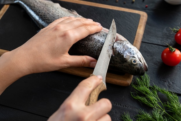 Photo gratuite cuisinier à angle élevé nettoyant le poisson dans la cuisine