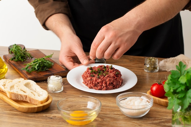 Photo gratuite cuisinier à angle élevé préparant un tartare de steak de boeuf