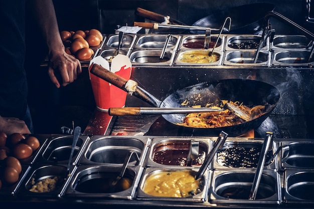 Le Cuisinier Fait Frire Des Légumes Avec Des épices Et De La Sauce Dans Un Wok. Processus De Cuisson Dans Un Restaurant Asiatique.