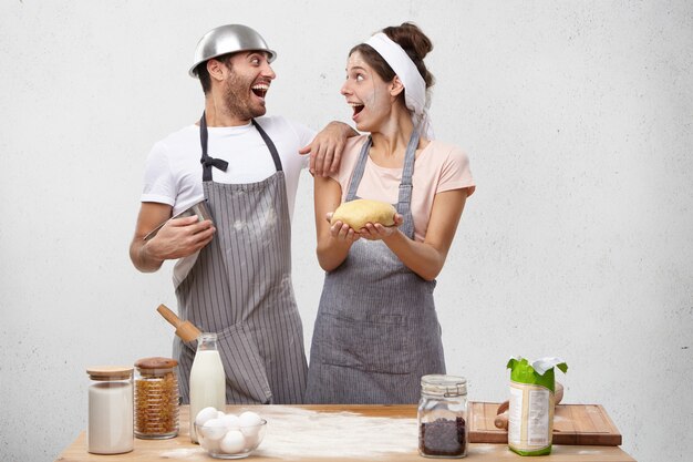 Les cuisiniers et cuisiniers excités se réjouissent de leur succès, se regardent avec le sourire, ont des expressions ravies