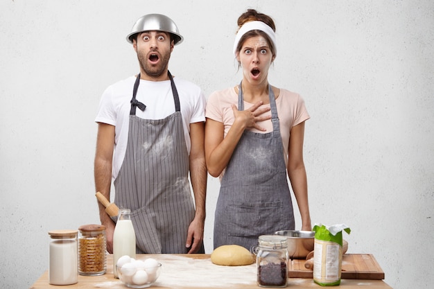 Les cuisiniers terrifiés, femmes et hommes, regardent avec la bouche largement ouverte, se tiennent à la cuisine