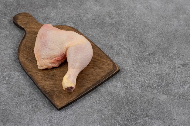 Cuisse de poulet crue sur planche à découper en bois