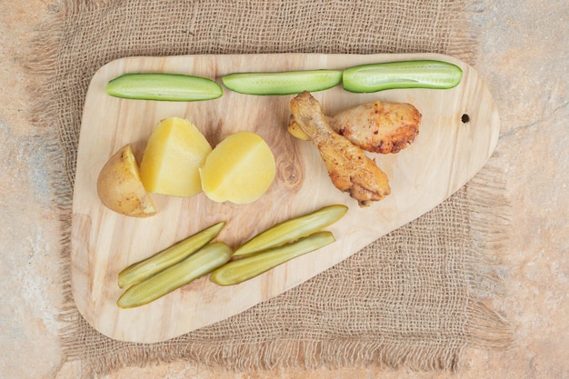 Cuisse de poulet avec divers légumes sur planche de bois