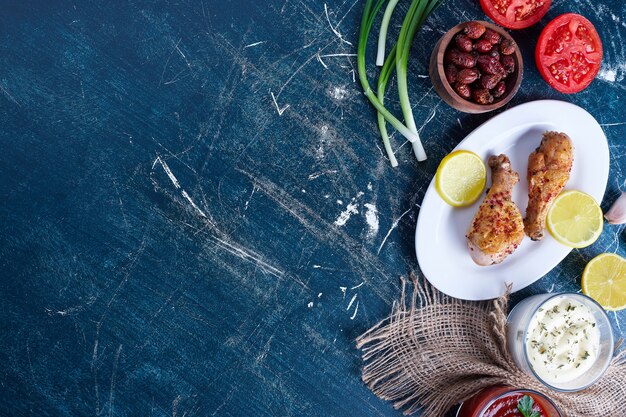 Cuisse de poulet frit épicé dans une assiette blanche avec du citron.