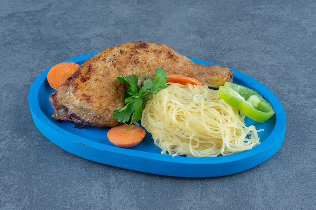 Cuisse de poulet frit et spaghetti sur plaque bleue.