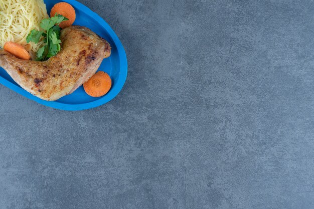 Cuisse de poulet frit et spaghetti sur plaque bleue.