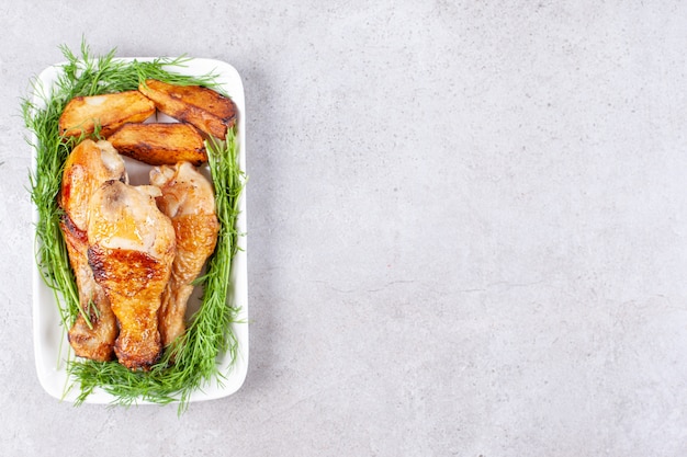 Cuisses de poulet au four avec des verts sur une plaque blanche