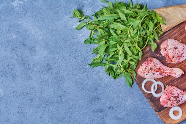 Cuisses de poulet aux herbes sur une planche de bois sur bleu