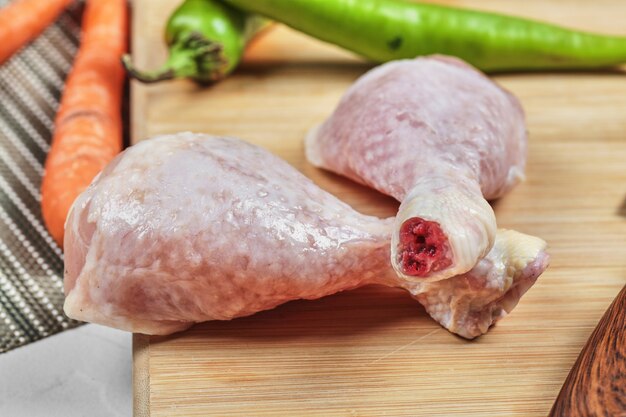 Cuisses de poulet cru sur planche de bois avec des piments