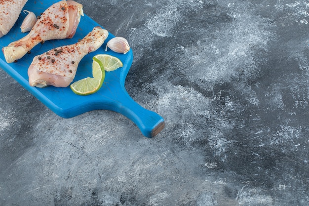 Cuisses de poulet crues épicées sur planche de bois bleue. Vue de dessus.