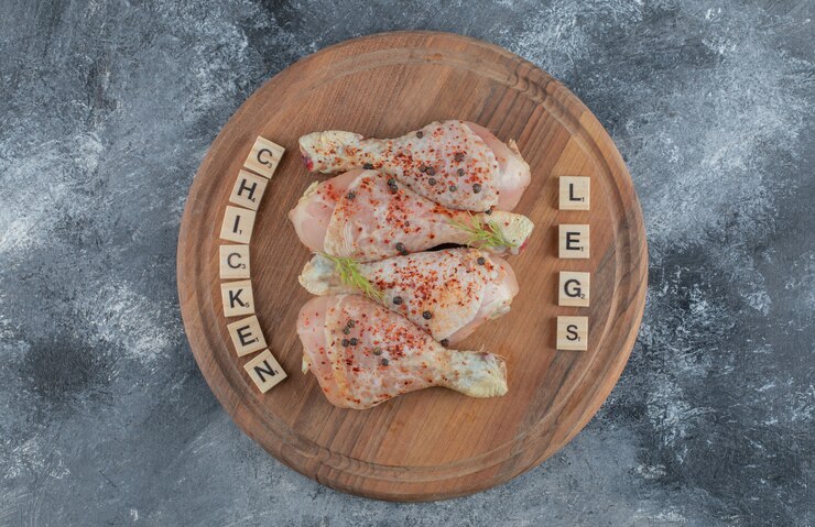 Photo gratuit cuisses de poulet crues marinées sur planche de bois.