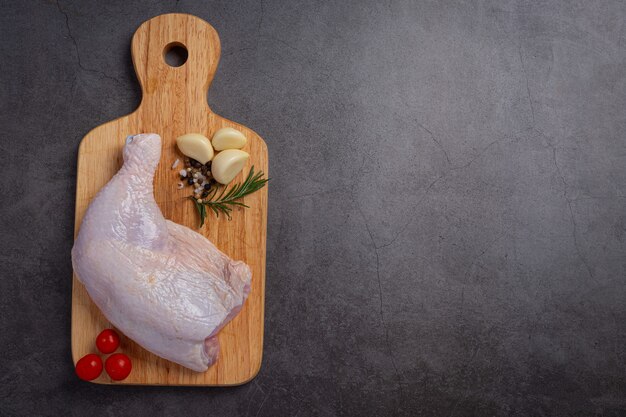 Cuisses de poulet crues sur la surface en bois sombre.