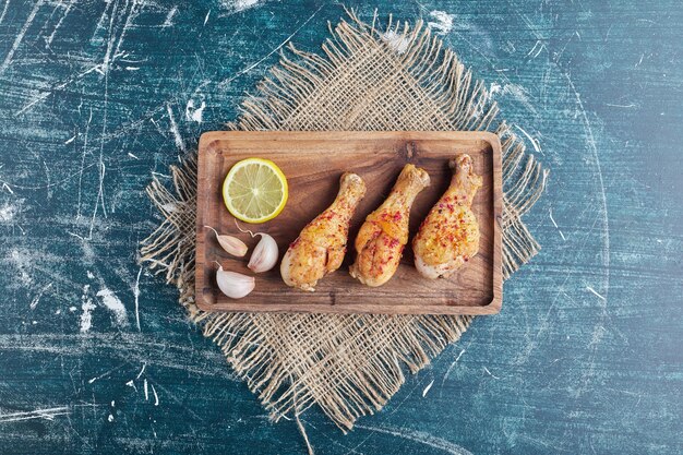 Photo gratuite cuisses de poulet épicées frites sur une planche de bois.