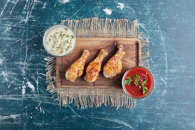 Cuisses de poulet frit sur une planche de bois avec des sauces.