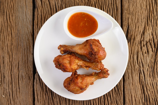 Cuisses de poulet frites sur une plaque blanche avec sauce.