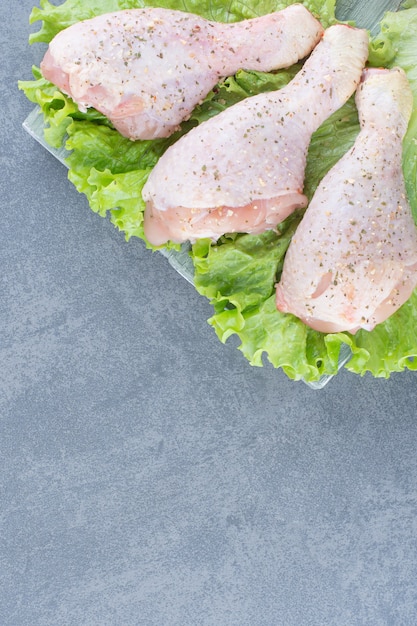 Photo gratuite cuisses de poulet non cuites avec de la laitue sur planche de bois.