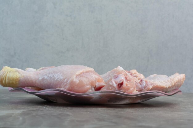 Cuisses de poulet non cuites sur plaque rose. photo de haute qualité