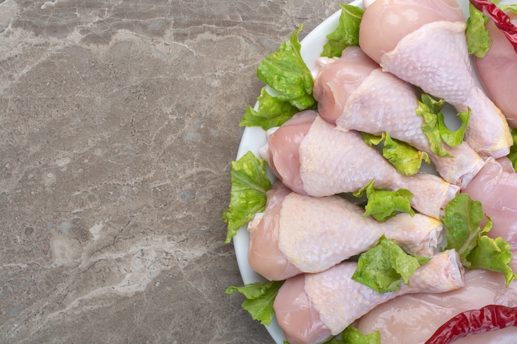 Photo gratuit cuisses de poulet non préparées avec de la laitue sur plaque blanche