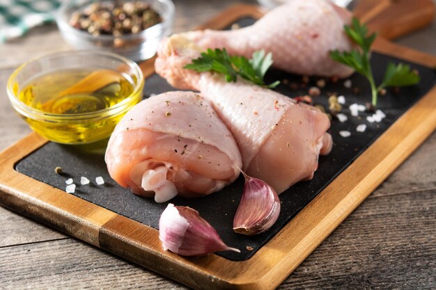 Cuisses de viande de poulet cru avec des épices et des herbes sur une planche à découper