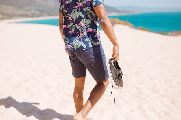 Photo gratuite culture mâle marchant pieds nus sur la plage de sable fin