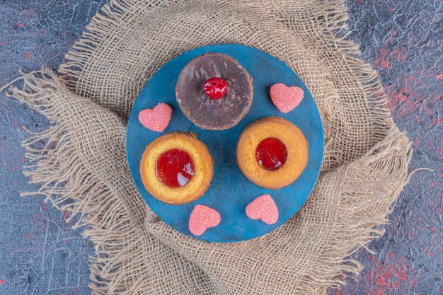 Cupcake au chocolat avec gâteaux et marmelades remplis de gelée sur un tableau bleu sur tableau abstrait.