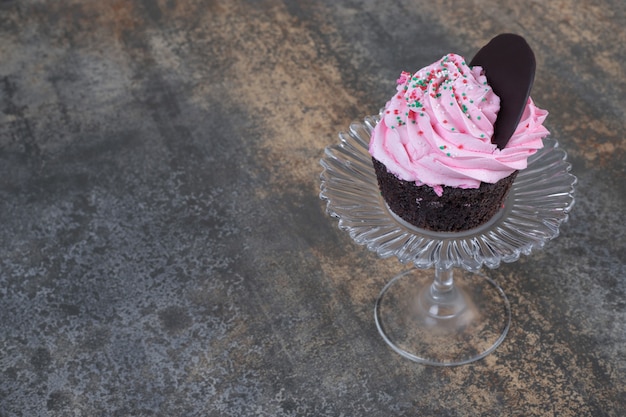 Photo gratuite cupcake crémeux rose sur plaque de verre sur marbre.