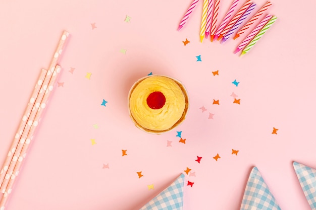Cupcake et décorations d'anniversaire sur fond rose