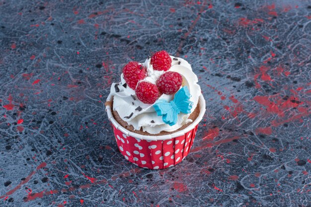 Cupcake garni de crème dans un cas de galette sur tableau abstrait.