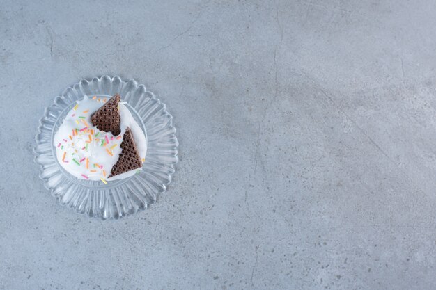 Cupcake savoureux décoré de crème et de vermicelles sur plaque de verre.